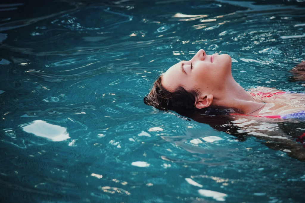 Jeune femme allongée dans l’eau profitant pleinement de sa piscine
